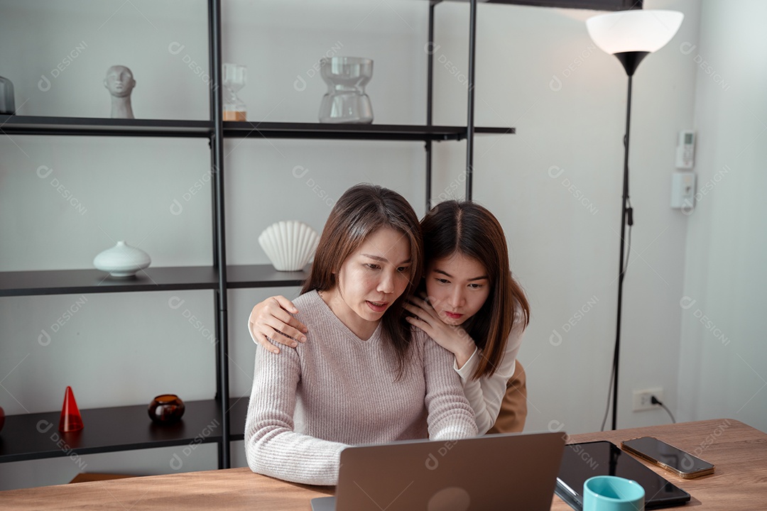 Família asiática, mãe e filha usando laptop juntas