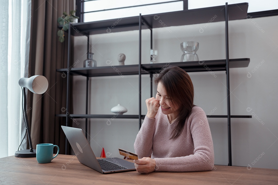 Mulher jovem asiática comprando on-line ou feliz com o uso de laptop na mesa