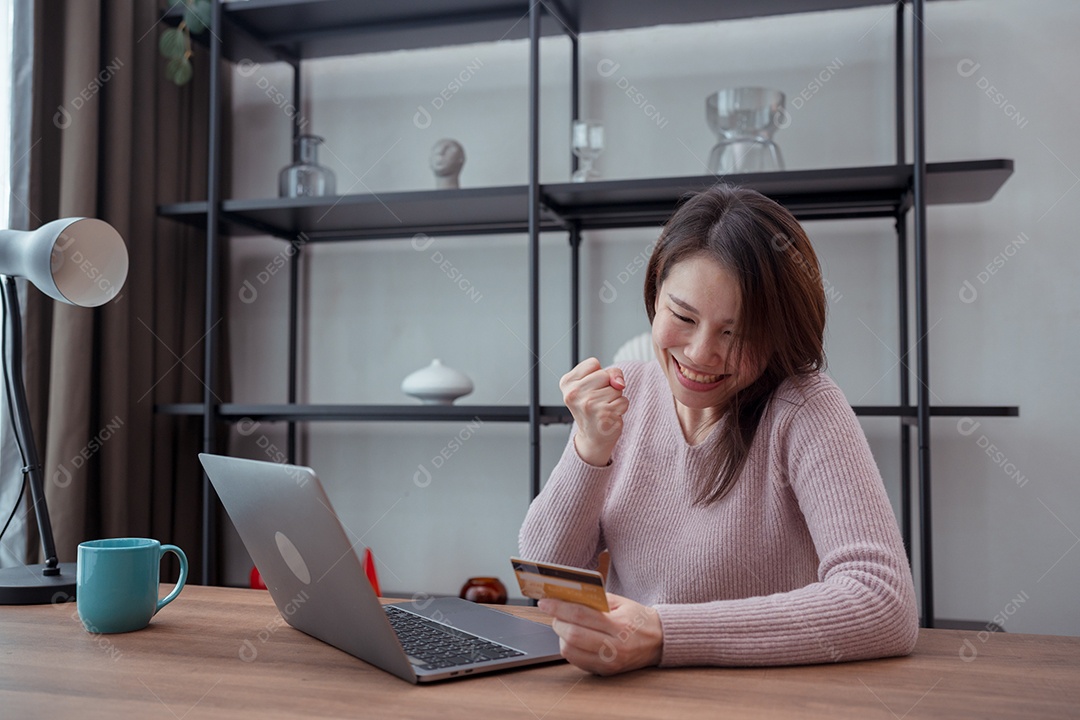 Mulher jovem asiática comprando on-line ou feliz com o uso de laptop na mesa