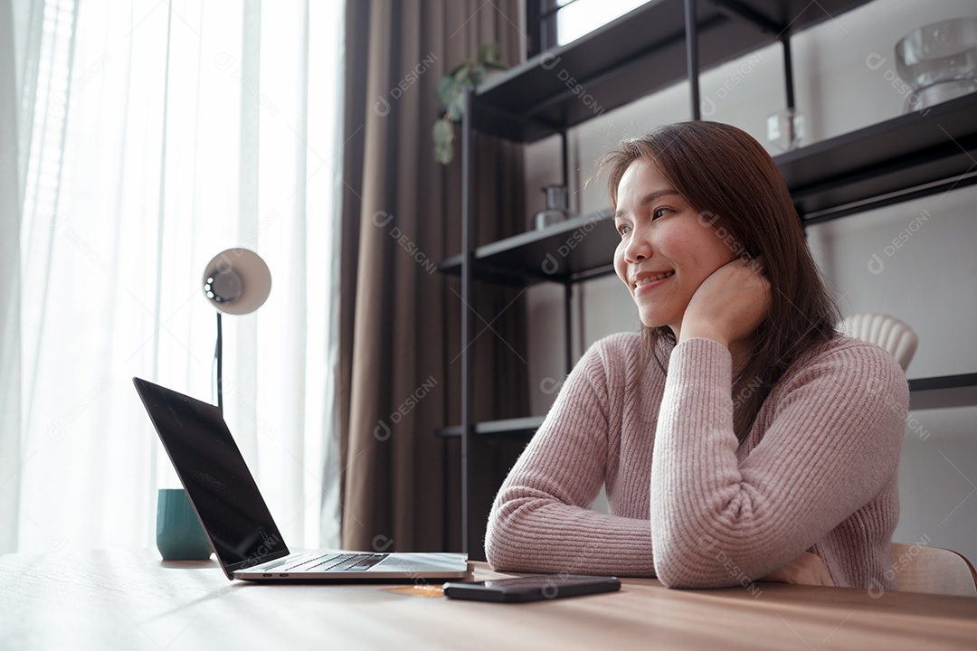 Mulher jovem asiática comprando on-line ou feliz com o uso de laptop na mesa