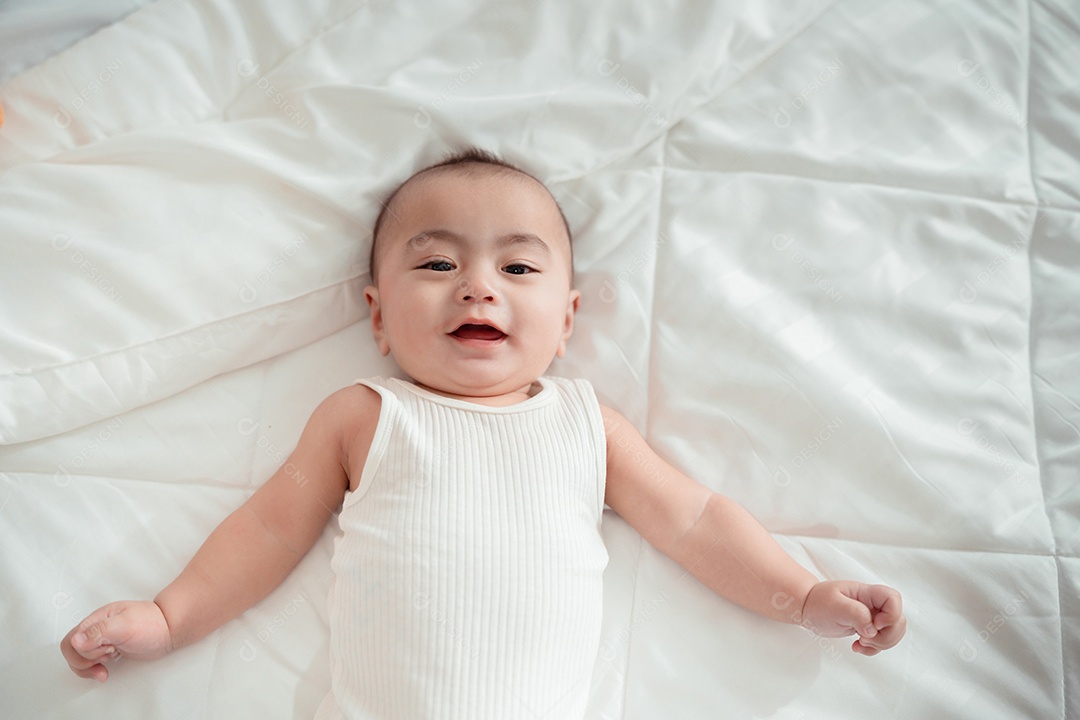 Bebê recém-nascido deitado em uma cama branca em casa.