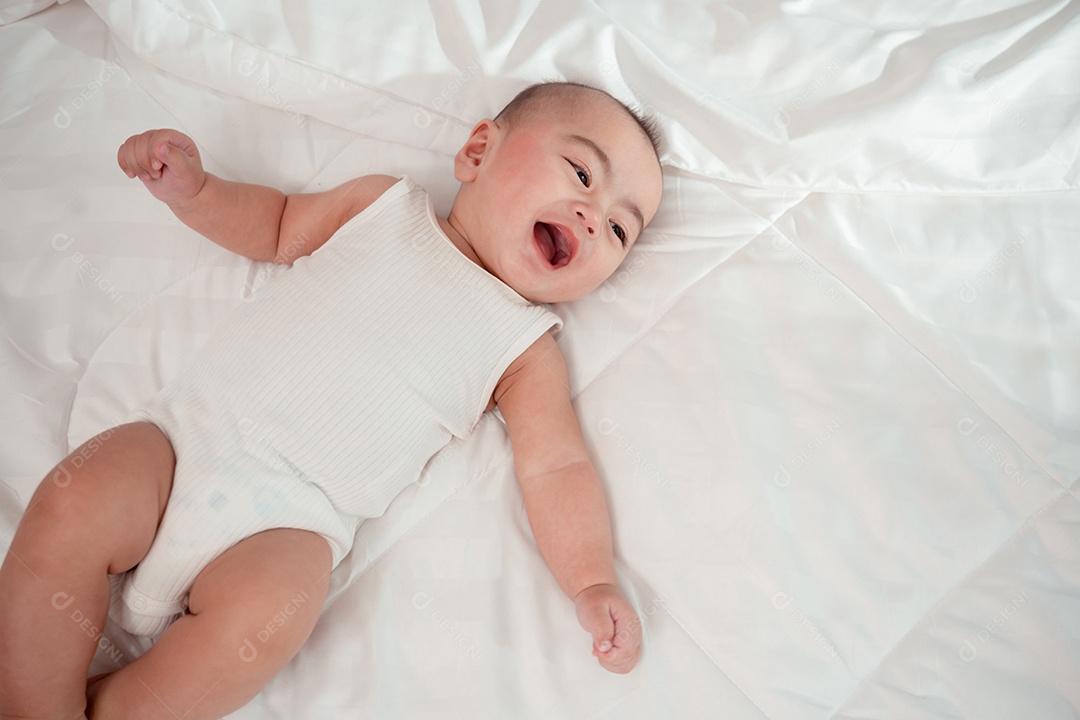 Bebê recém-nascido deitado em uma cama branca em casa.