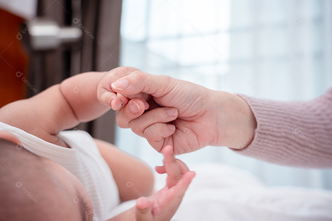 As mãos segurando os dedos do bebê recém-nascido