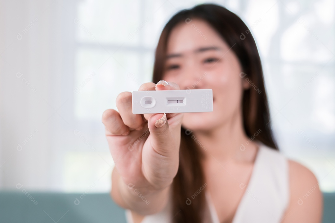 Mulher asiática mostrando kit de teste rápido de antígeno para autoteste com resultado negativo