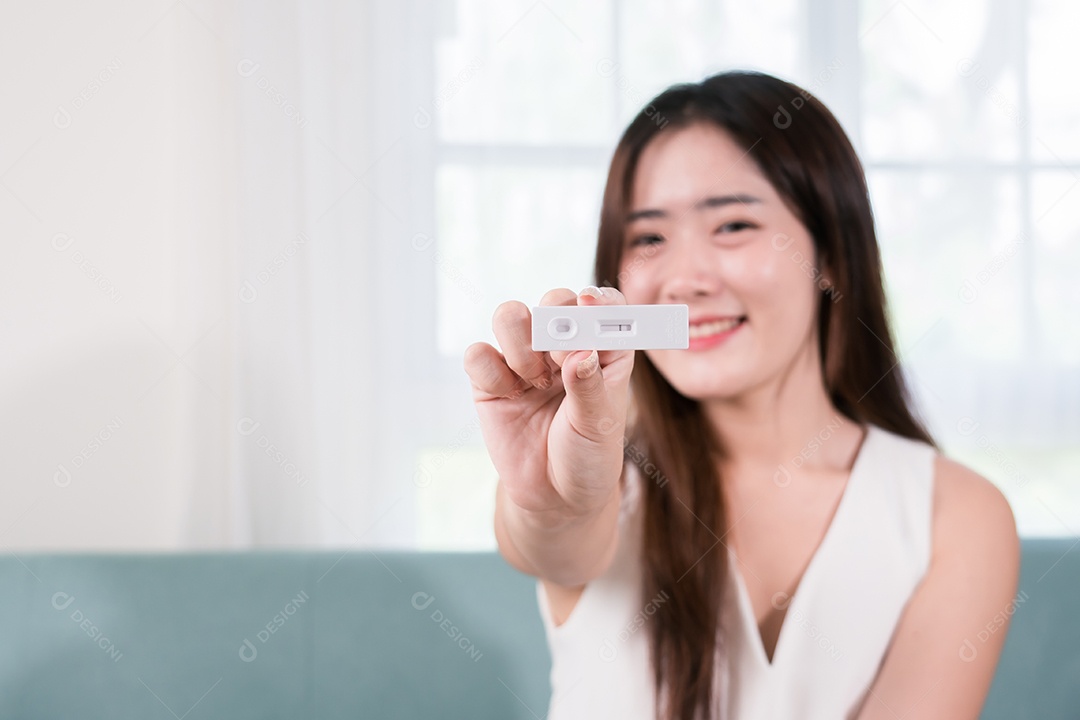 Mulher asiática mostrando kit de teste rápido de antígeno para autoteste com resultado negativo