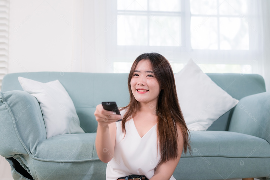Mulher asiática usa controle remoto para assistir tv