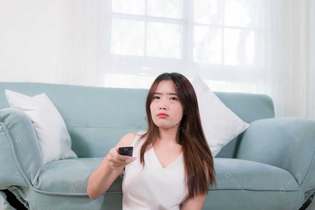 Mulher asiática usa controle remoto para assistir tv