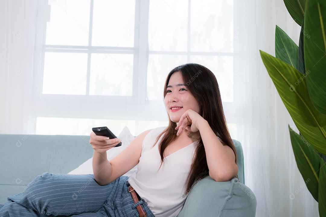 Mulher asiática usa controle remoto para assistir tv