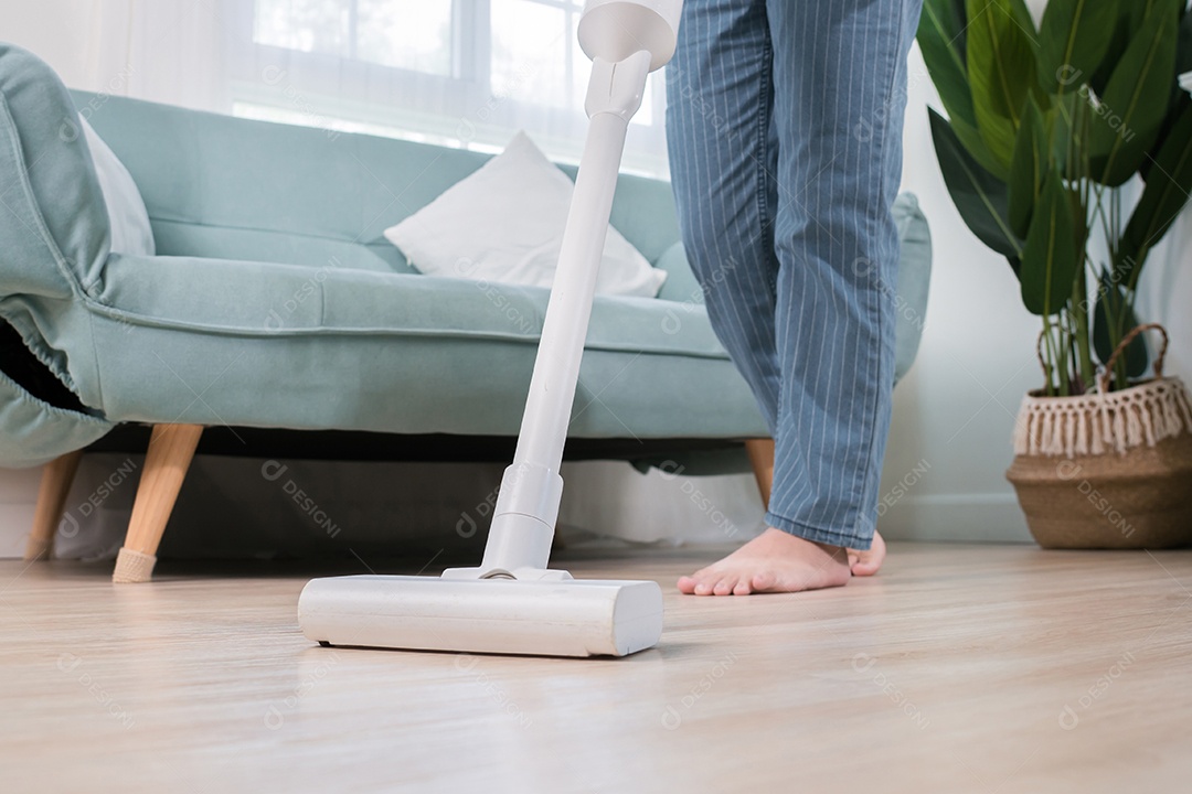 Mulher asiática feliz usando aspirador de pó enquanto limpa o chão em casa