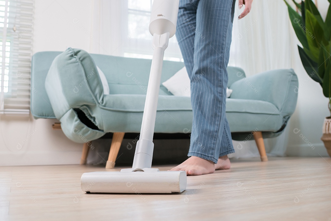 Mulher asiática feliz usando aspirador de pó enquanto limpa o chão em casa