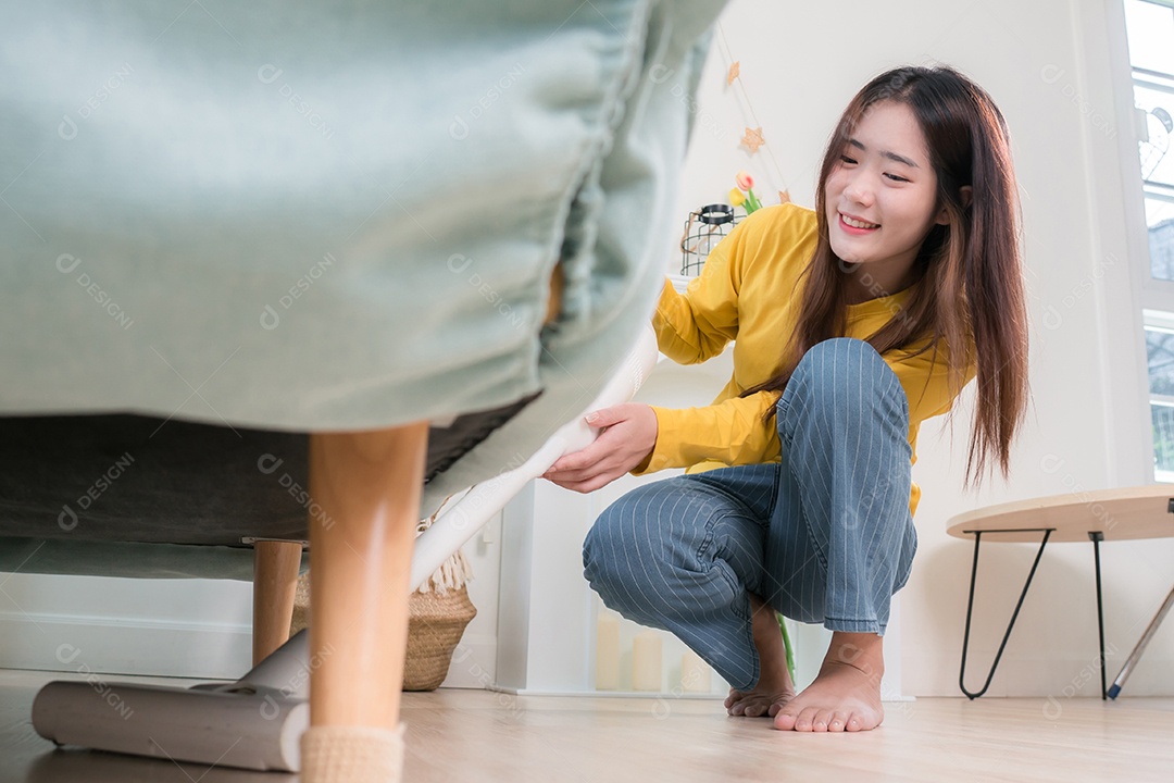 Mulher asiática feliz usando aspirador de pó enquanto limpa o chão em casa