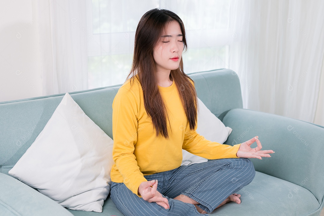 Mulher meditando no sofá da sala de estar