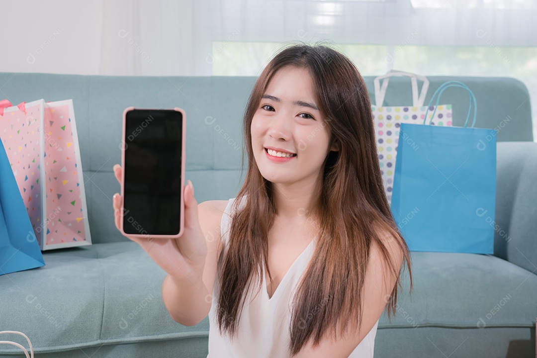 Mulher asiática sorridente apresenta celular para conteúdo de publicidade