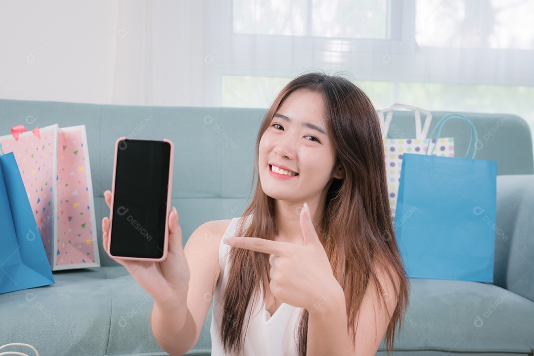 Mulher asiática sorridente apresenta celular para conteúdo de publicidade