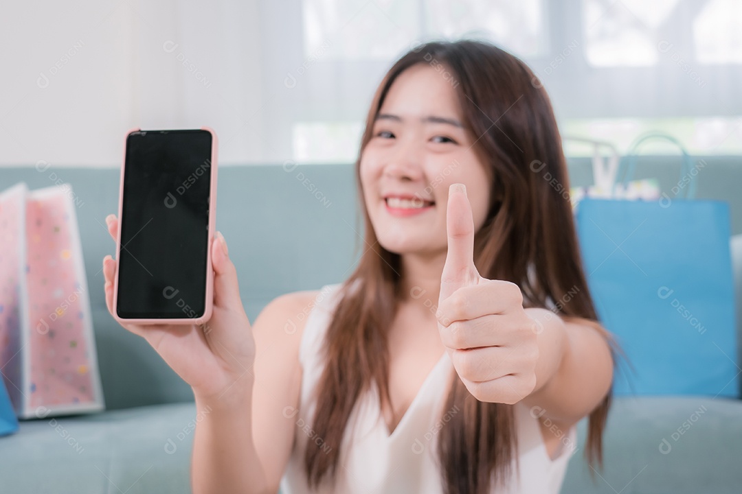 Mulher asiática sorridente apresenta celular para conteúdo de publicidade