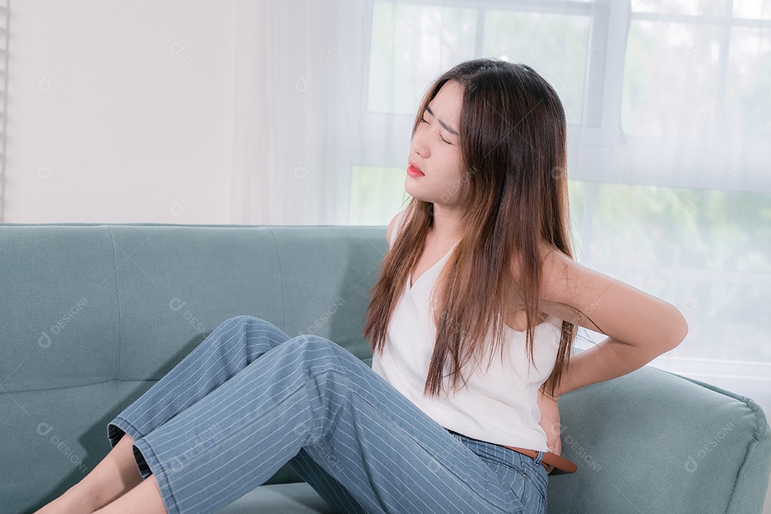 Mulher asiática ela tem dor nas costas no sofá na sala de estar em casa