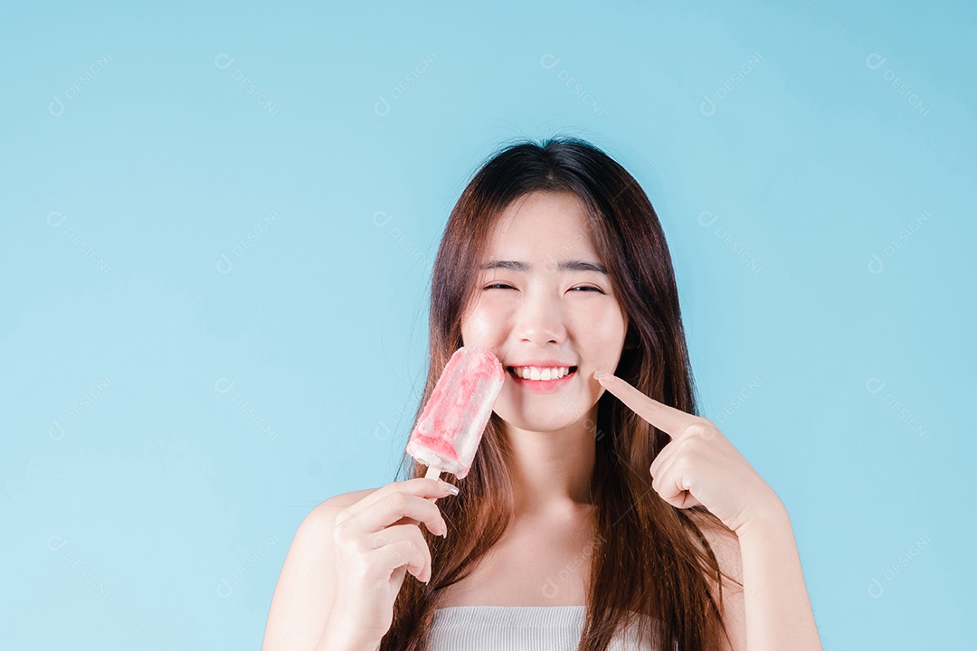 Mulher asiática segura picolé tem dentes hipersensíveis no fundo azul