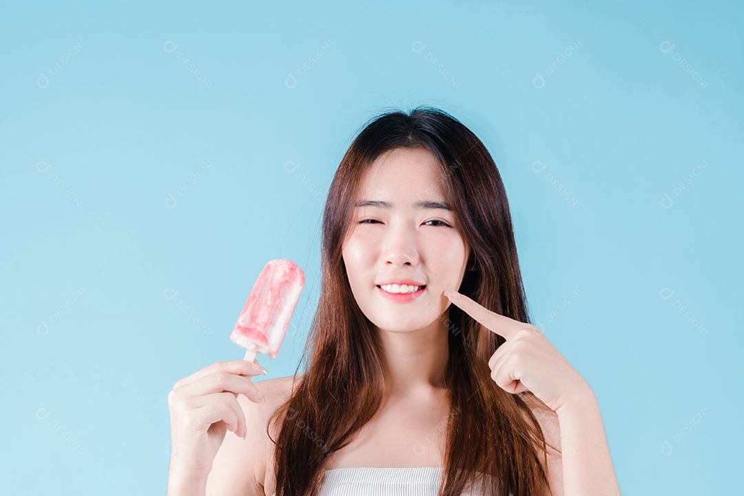 Mulher asiática segura picolé tem dentes hipersensíveis no fundo azul