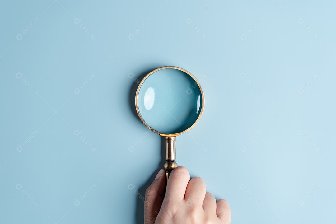 Mãos de mulher segurando lupa em fundo azul