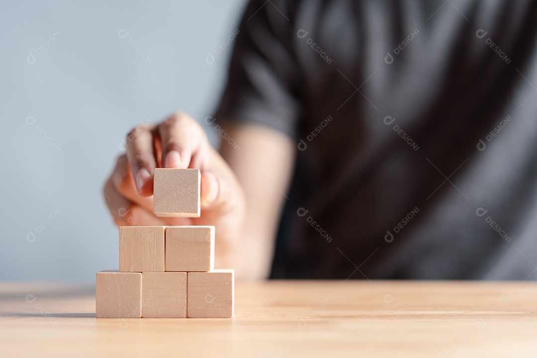 Mão de homem sobre blocos de madeira empilhados