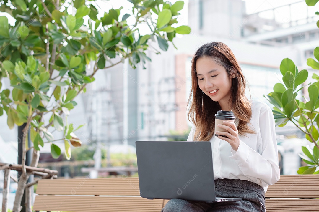 Linda empresária sentada no banco usando computador