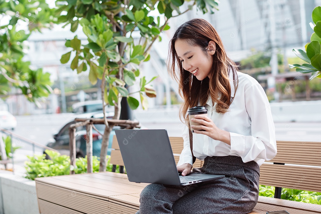 Linda empresária sentada no banco usando computador