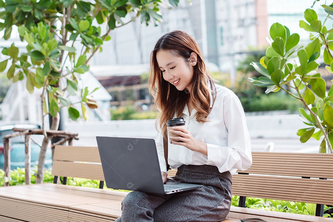 Linda empresária sentada no banco usando computador