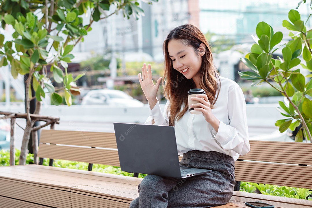 Linda mulher empresária sentada no banco usando computador