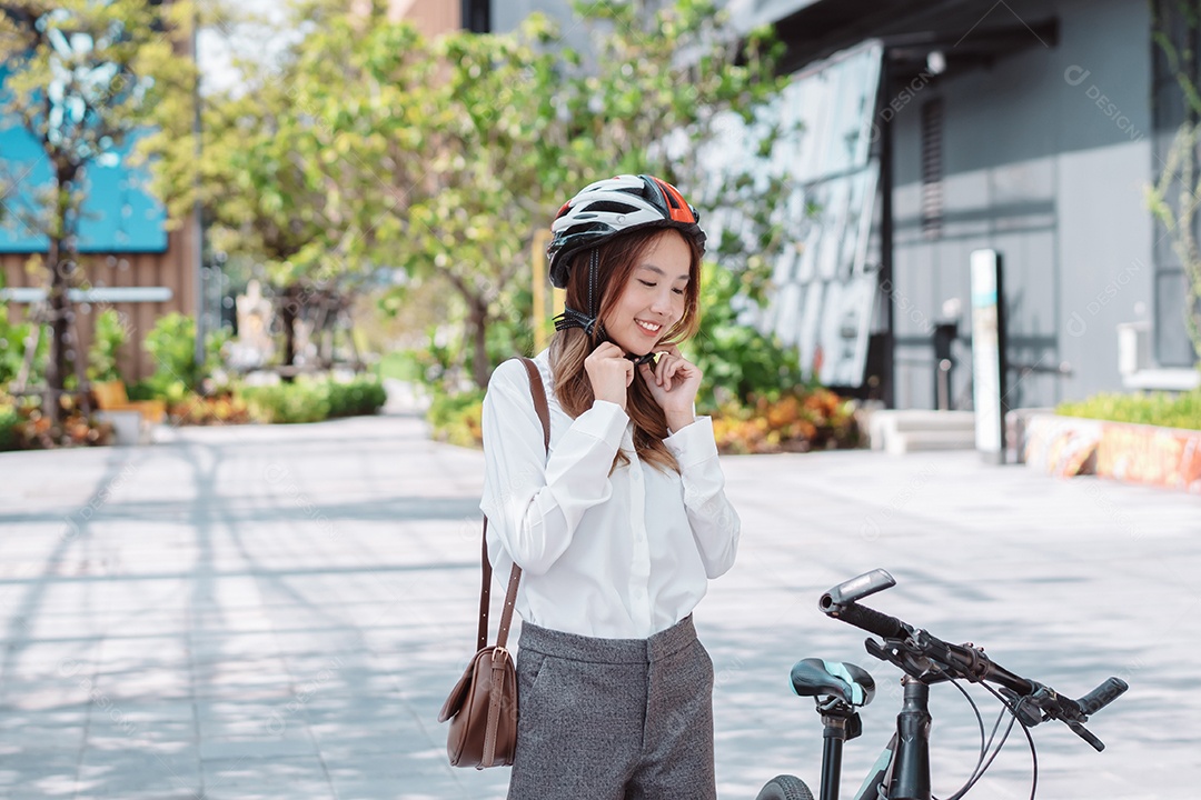 Mulher asiática andando de bicicleta com capacete de segurança