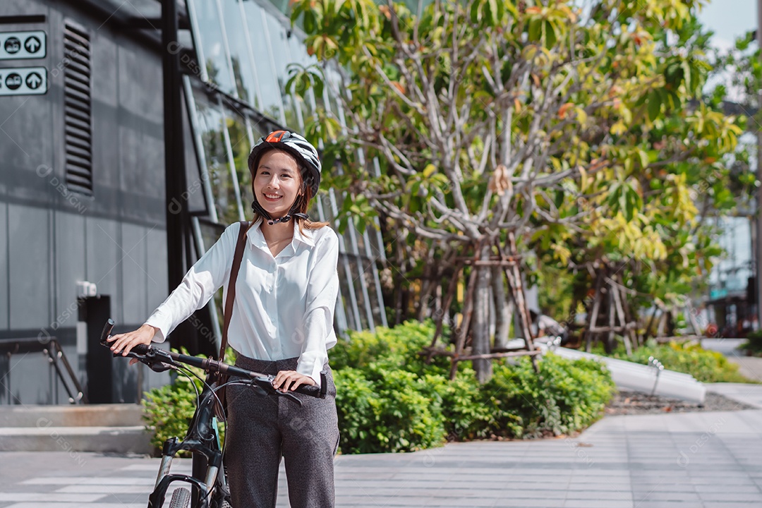 Linda mulher asiática com capacete de segurança andando de bicicleta