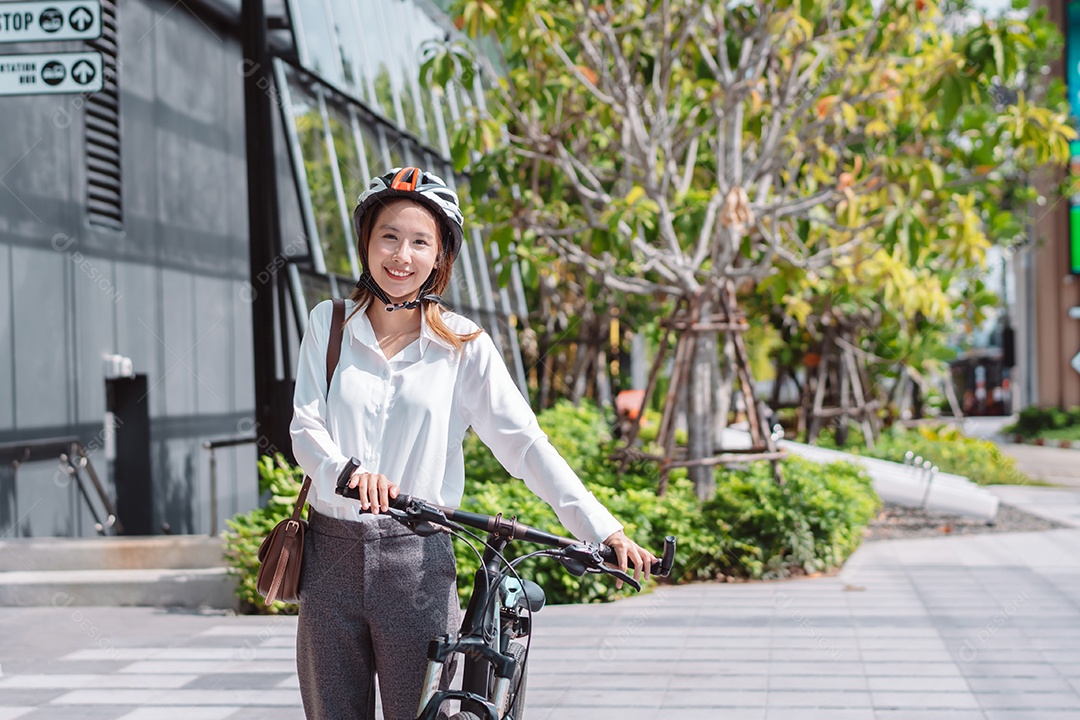 Linda mulher asiática com capacete de segurança andando de bicicleta