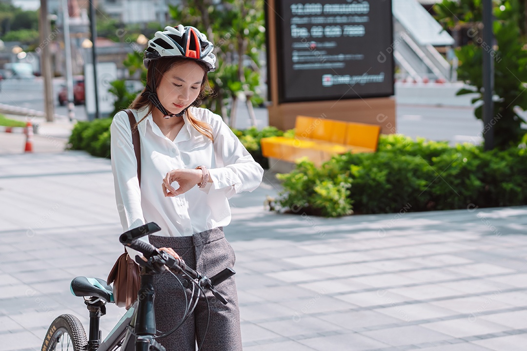 Linda mulher asiática com capacete de segurança andando de bicicleta