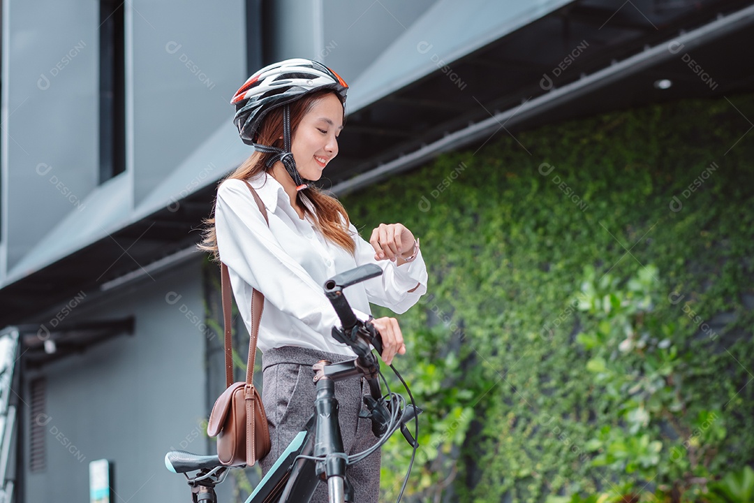 Linda mulher asiática sorridente com capacete de segurança andando de bicicleta