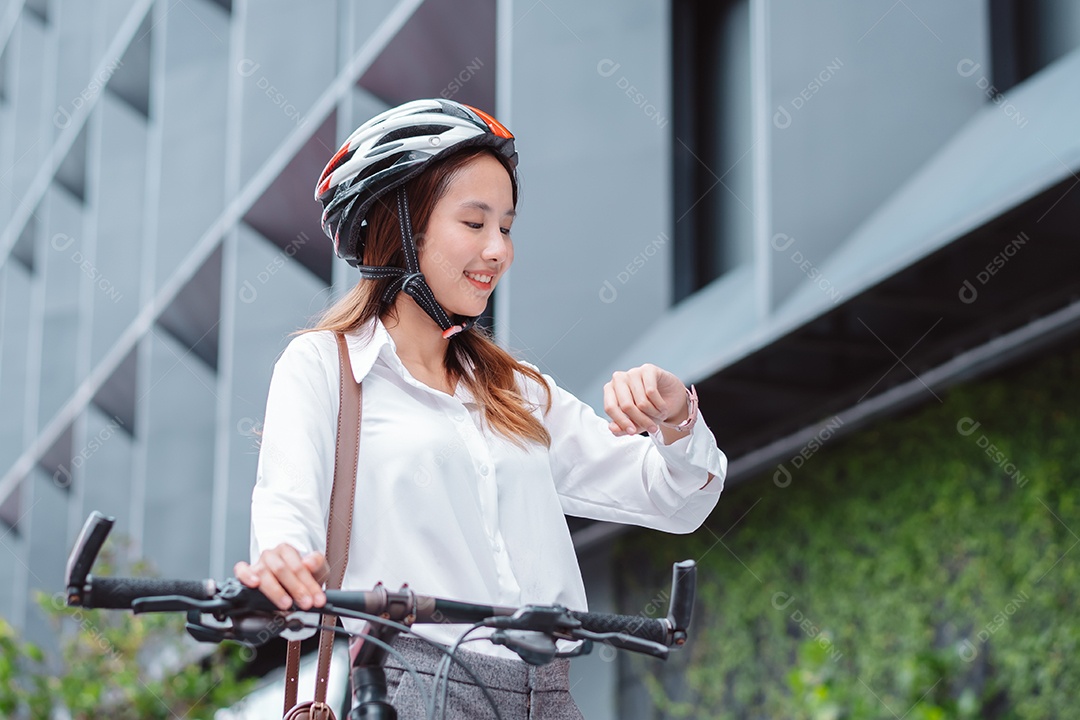 Linda mulher asiática sorridente com capacete de segurança andando de bicicleta
