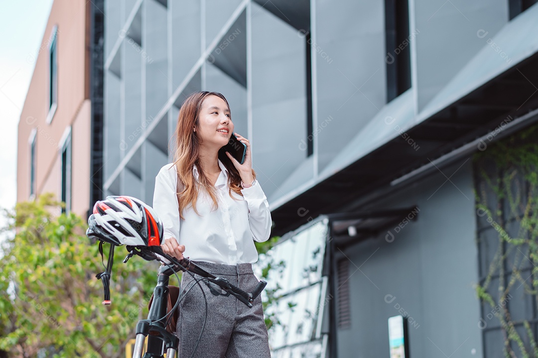 Linda mulher asiática sorridente com bicicleta falando ao celular