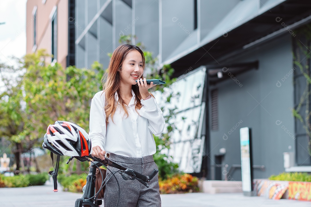 Linda mulher asiática sorridente com bicicleta falando ao celular