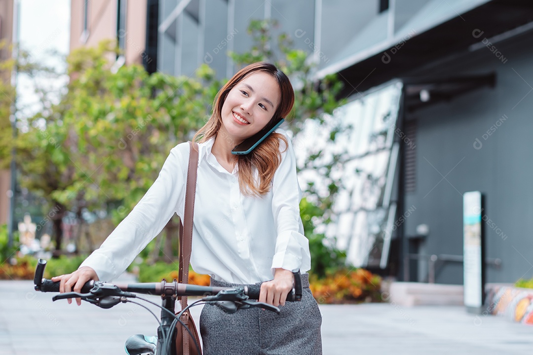 Linda mulher asiática sorridente com bicicleta falando ao celular