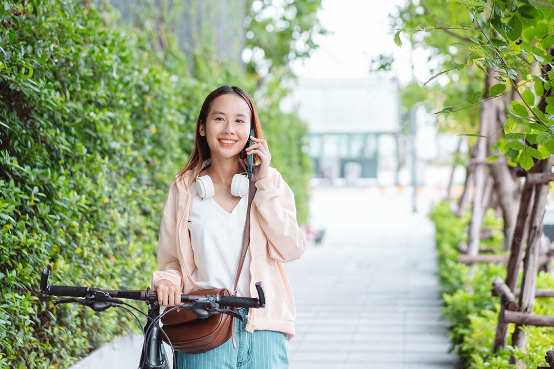 Linda mulher sorridente andando de bicicleta falando ao celular