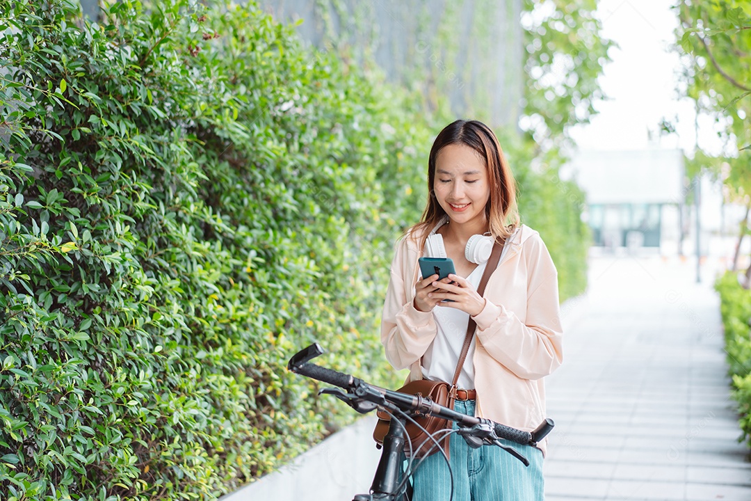 Linda mulher sorridente andando de bicicleta usando celular