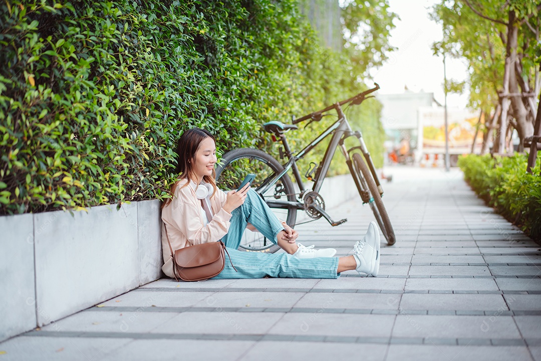Linda mulher asiática sentada na calçada usando celular