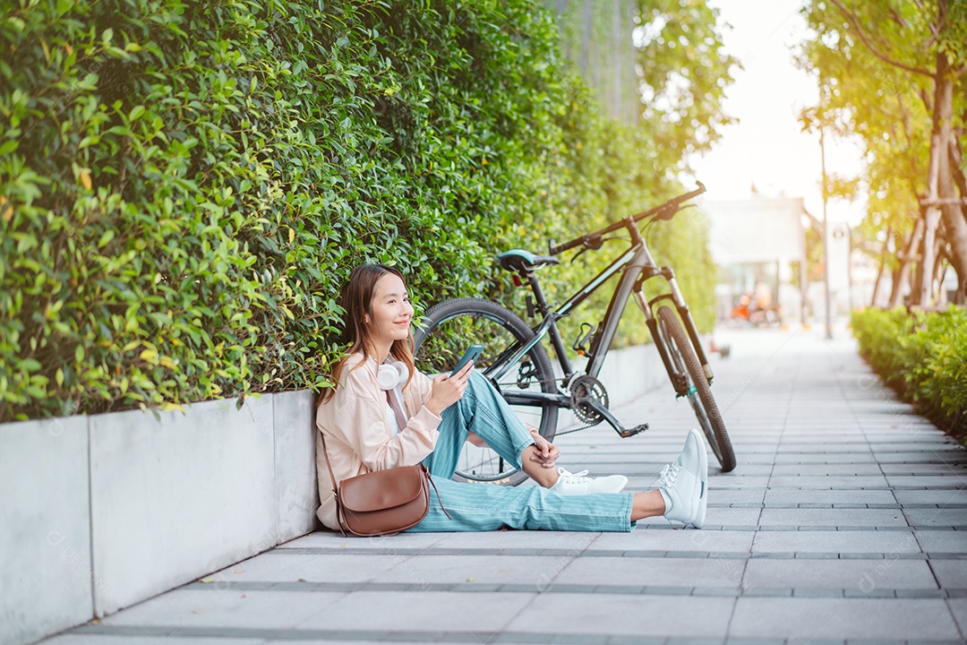 Linda mulher asiática sentada na calçada usando celular