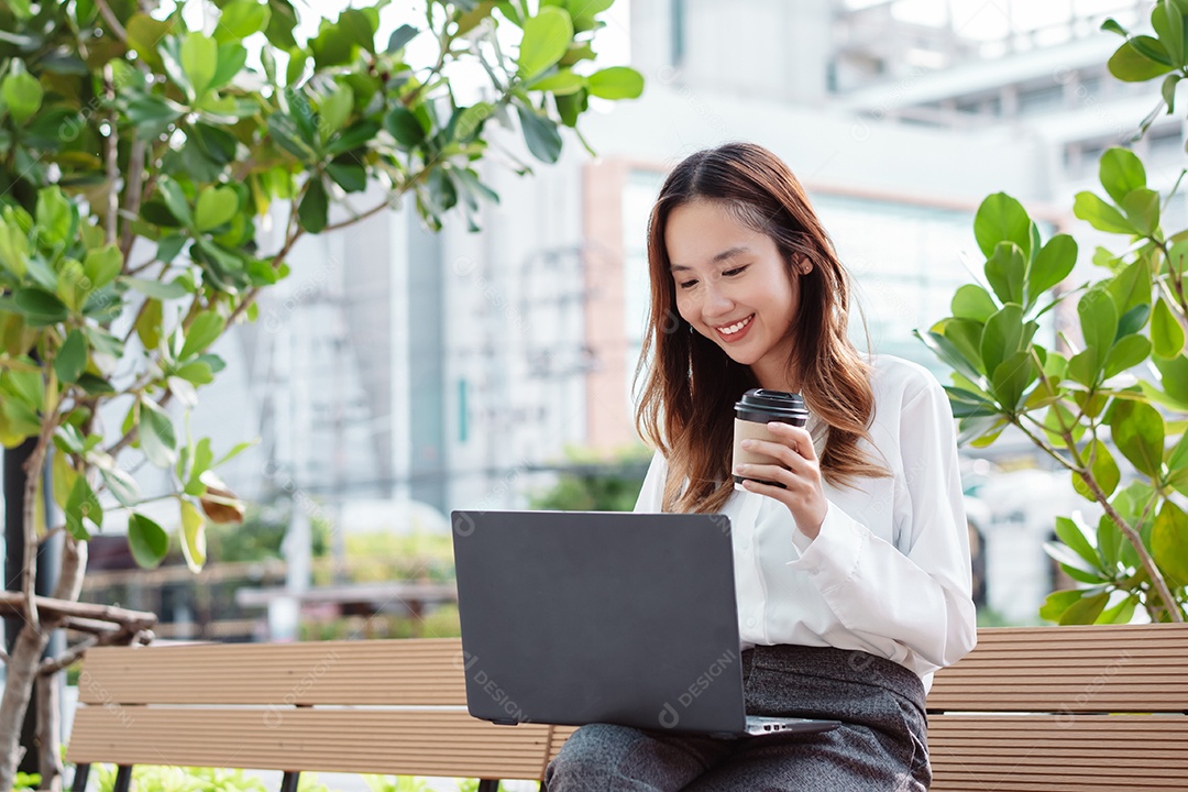 Empresária asiática usa computador portátil e telefone celular