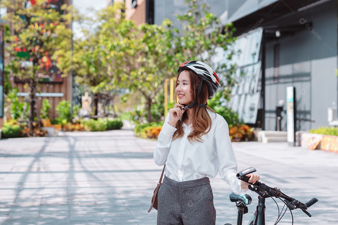 Empresária asiática usando capacete de segurança antes de ir para o trabalho de bicicleta