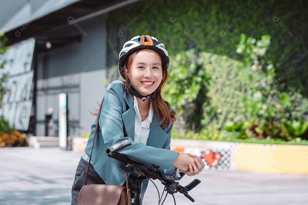 Empresária asiática usando capacete de segurança antes de ir para o trabalho de bicicleta