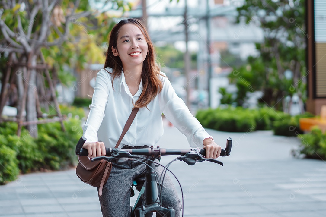 A confiança da empresária asiática vai para o trabalho de escritório na rua da cidade moderna com bicicleta