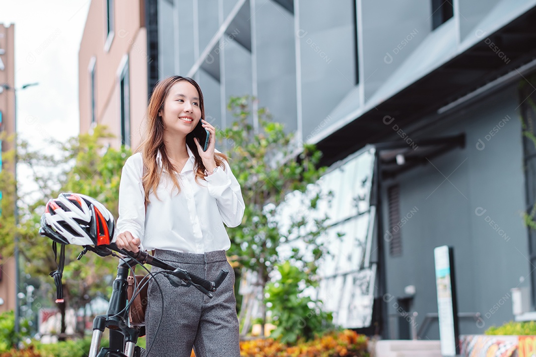 A mulher de negócios asiática usa o telefone celular inteligente durante o trabalho
