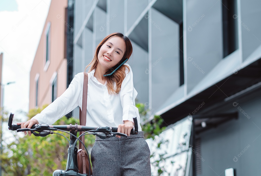 A mulher de negócios asiática usa o telefone celular inteligente durante o trabalho