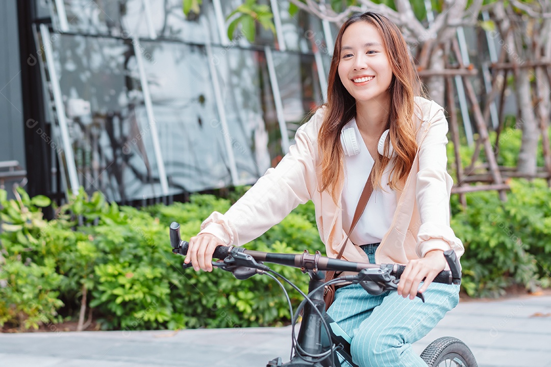 Feliz jovem asiática andar de bicicleta no parque
