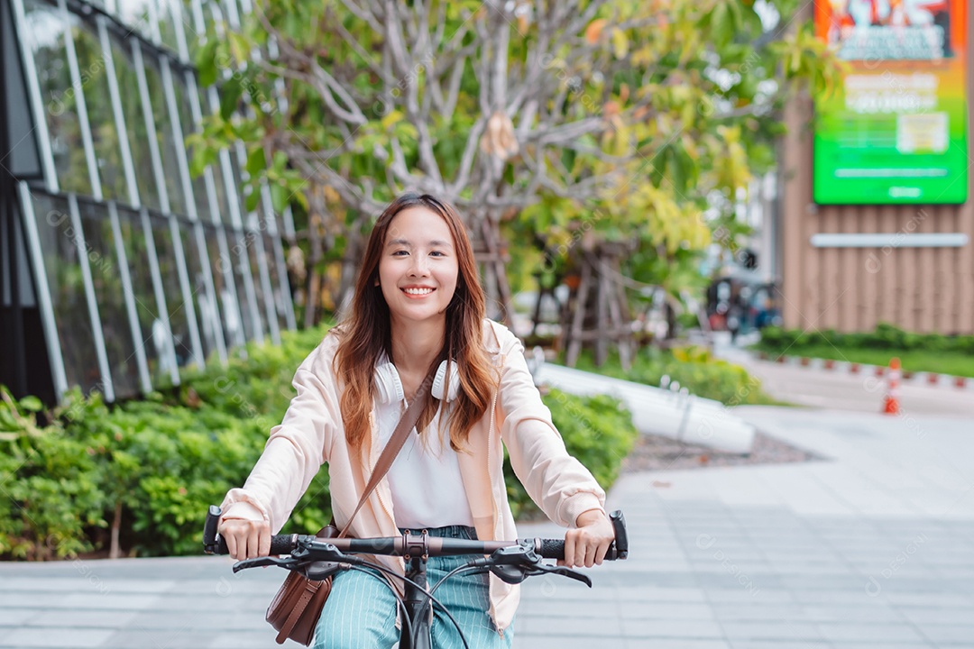 Feliz jovem asiática andar de bicicleta no parque