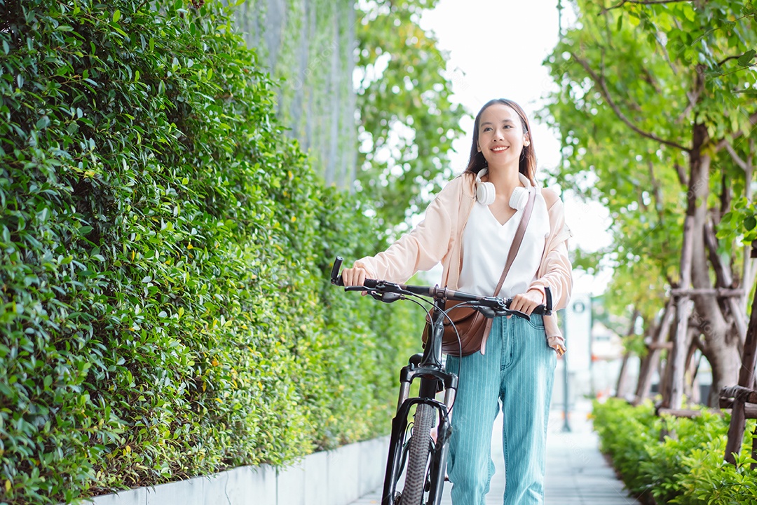 Uma jovem asiática feliz anda de bicicleta no parque